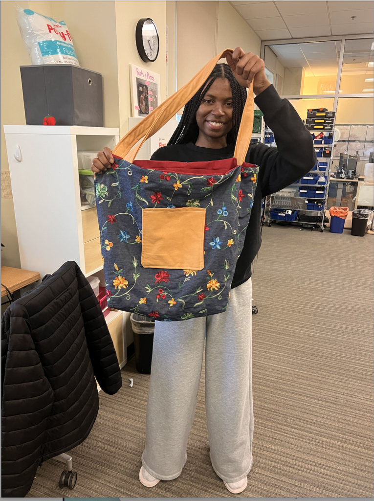 Young woman holding up finished tote bag project
