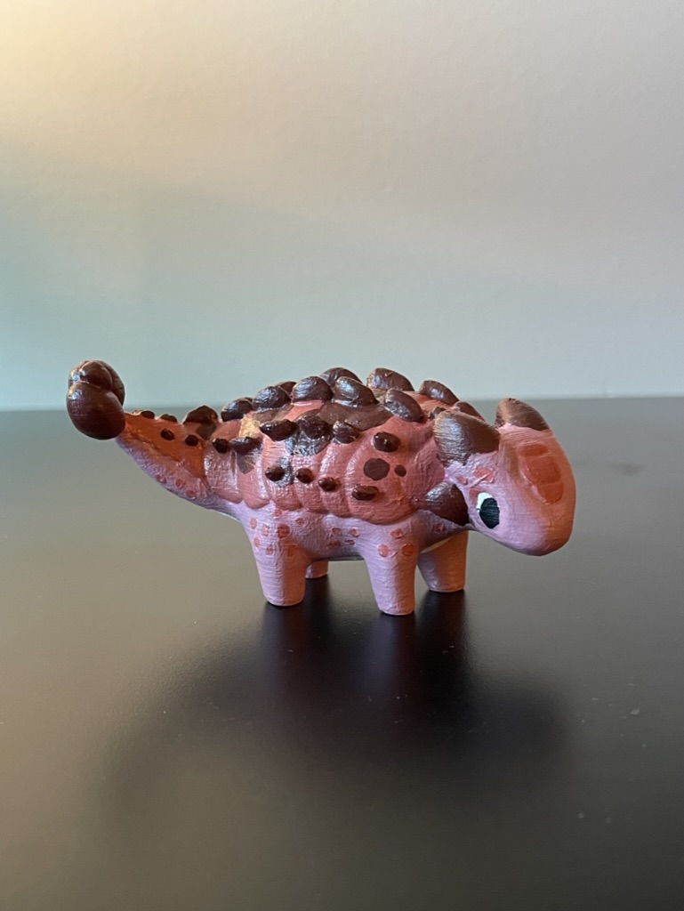 A 3D printed anklyosaurus dinosaur that has been painted shades of red and pink
