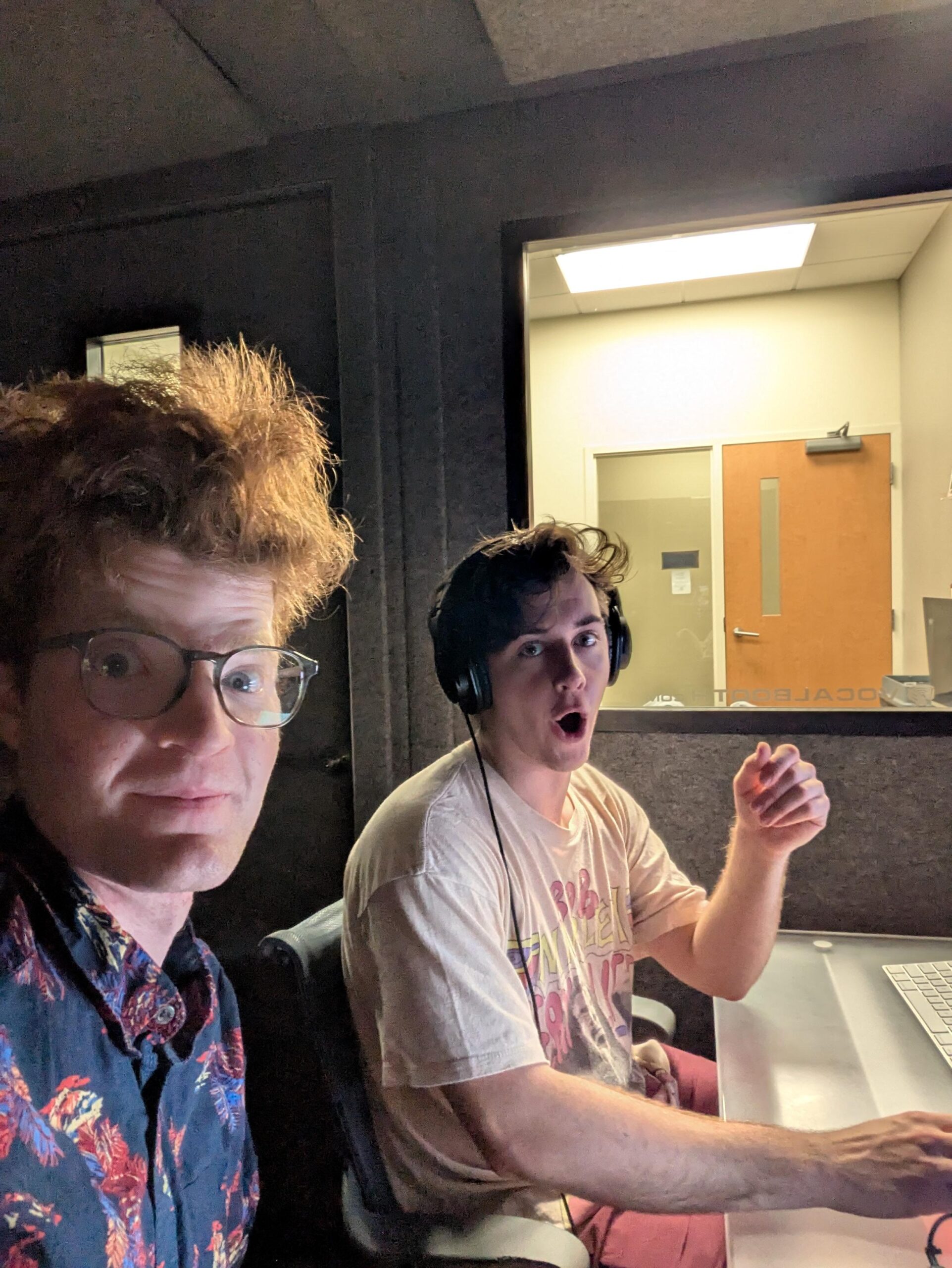two men in sitting at a computer station in a vocal recording booth
