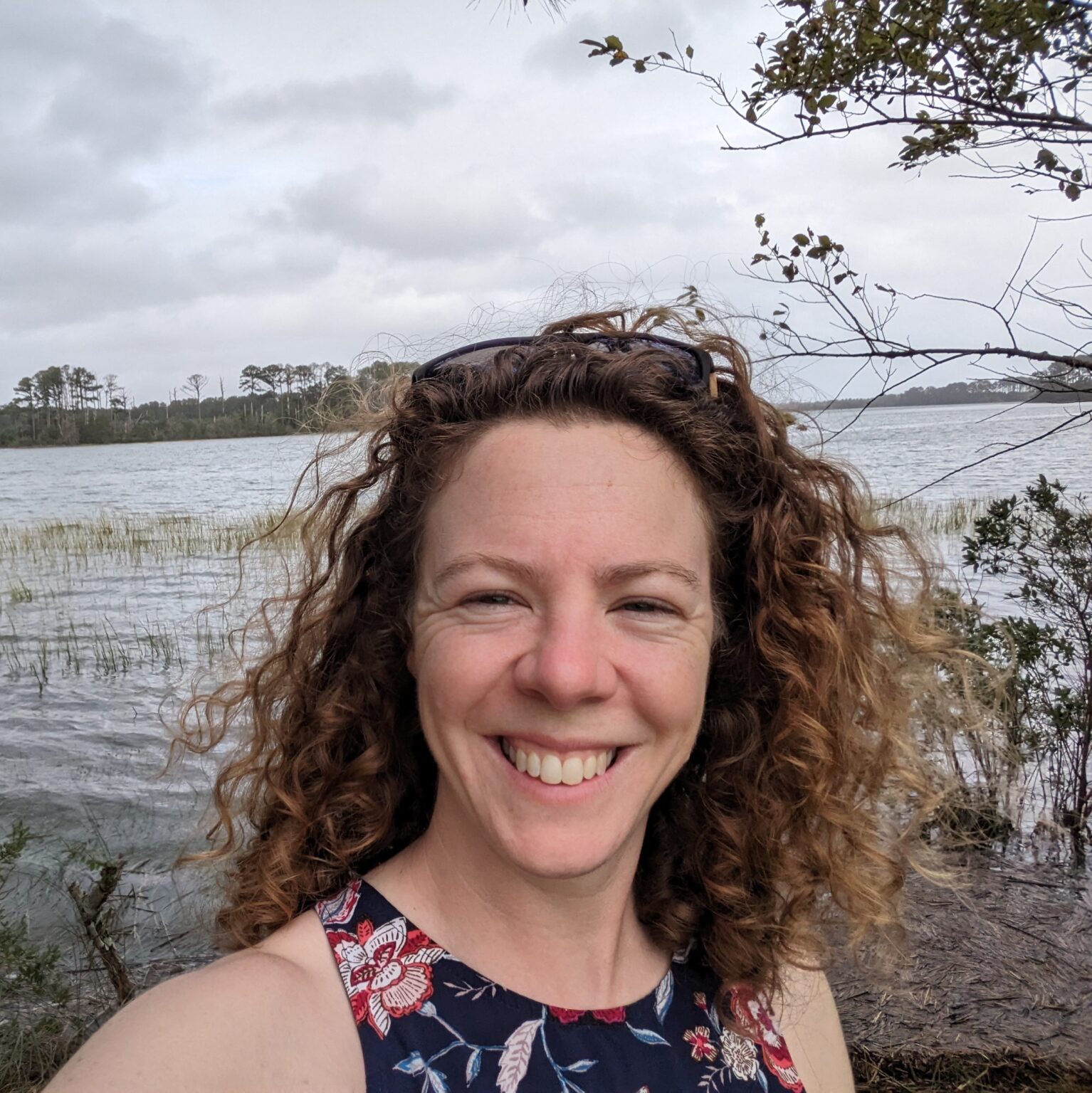 woman with curly long hair standing in front of a tidal creek